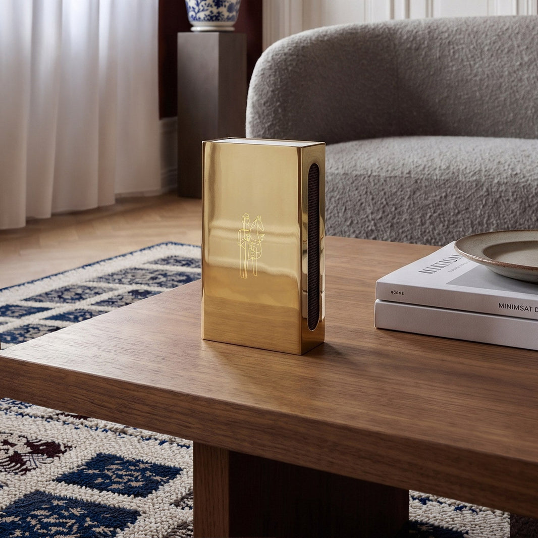 Woman with Horse matchbox case in polished brass on a walnut coffee table