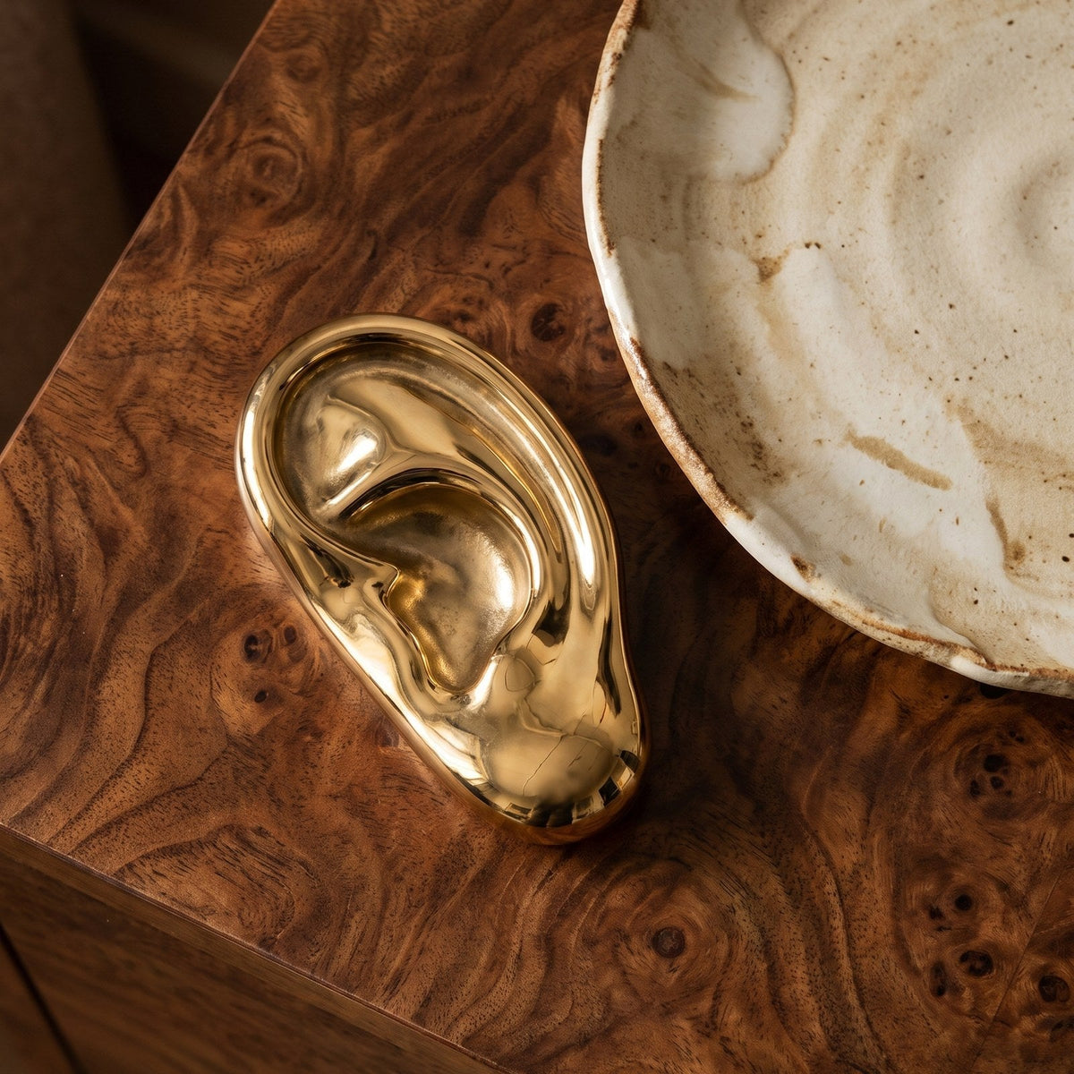 Vincent's Ear bottle opener in polished brass on a burl wood table