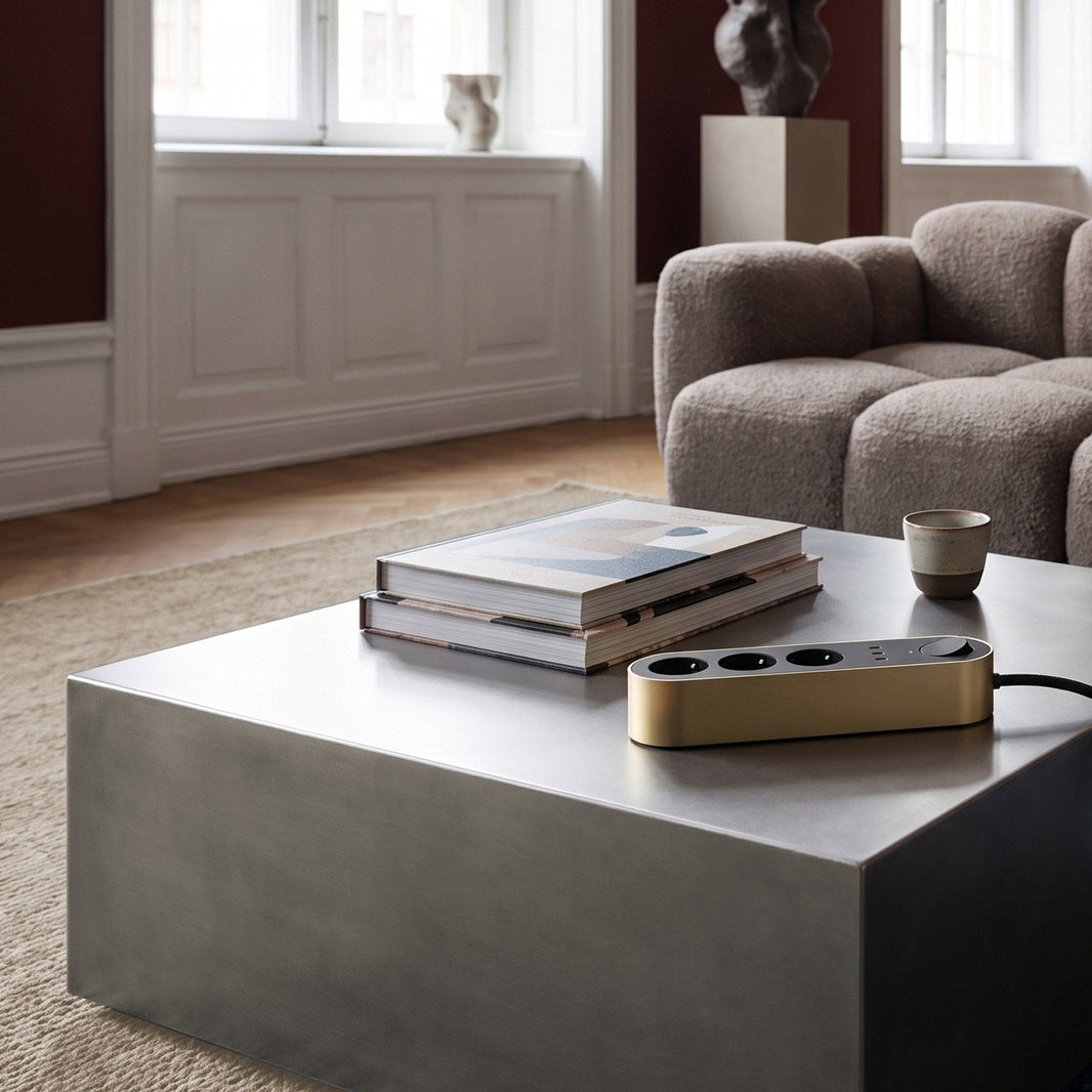 Edgar power strip in satin brass on a steel coffee table in a living room