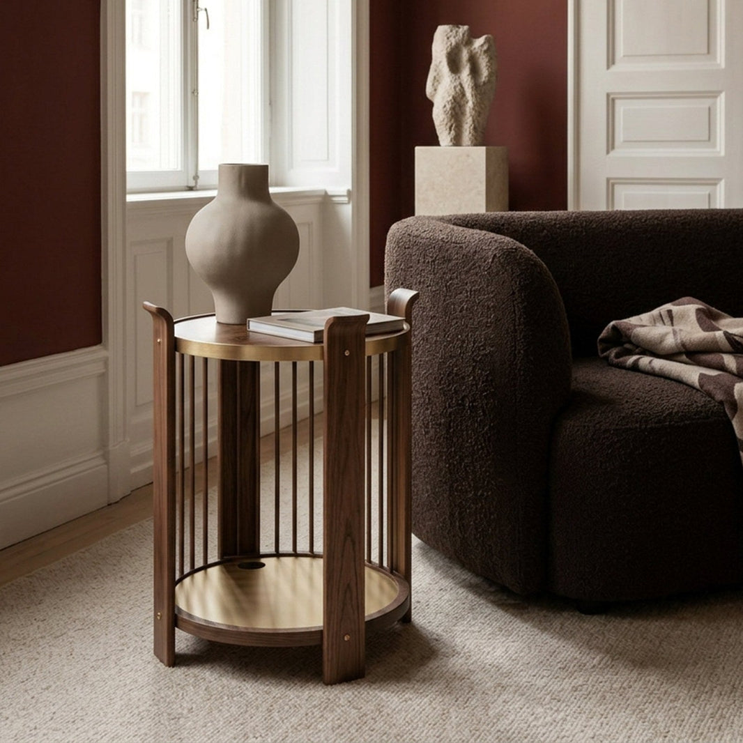 Karl side table in Swedish walnut with brass shelf next to a boucle armchair