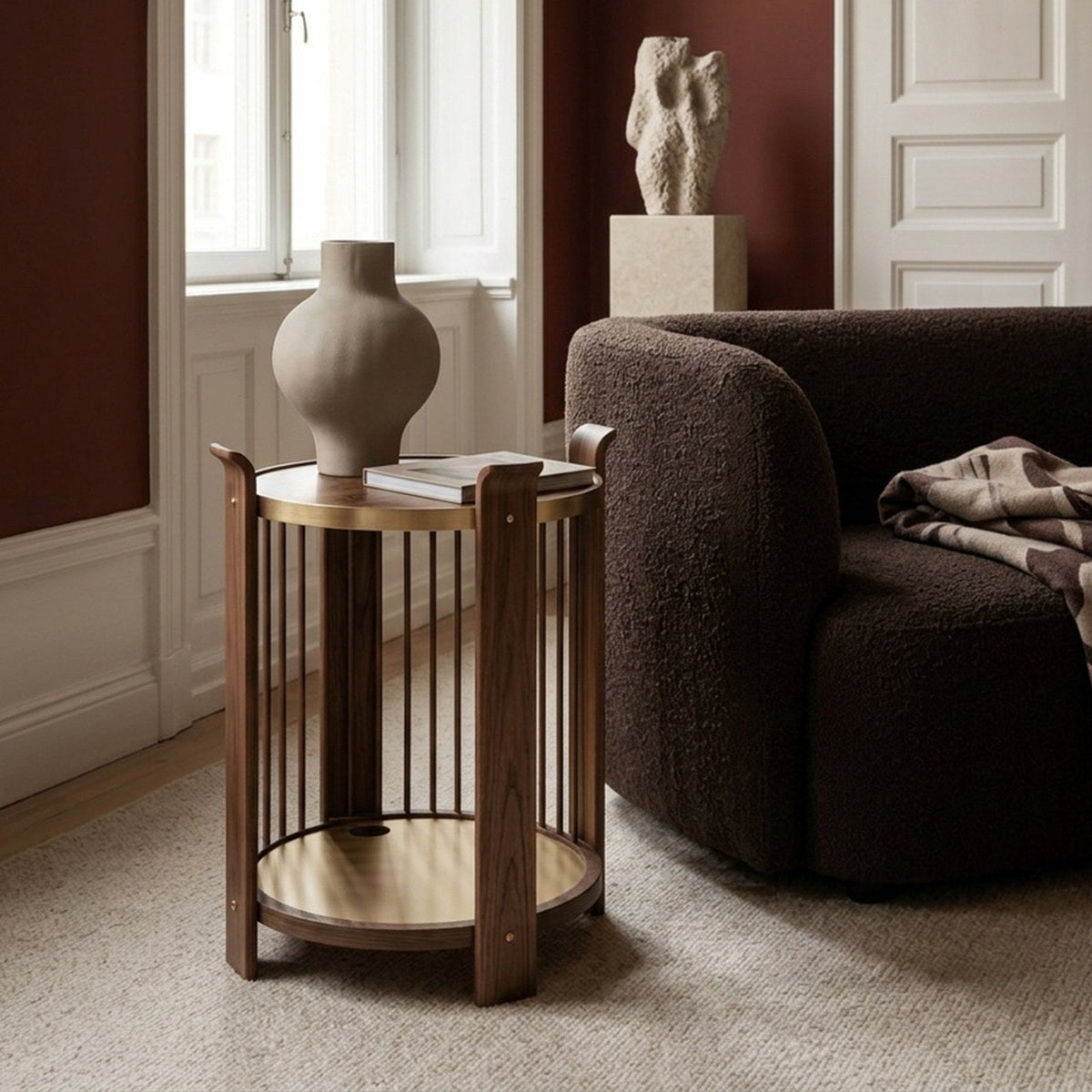 Karl side table in Swedish walnut with brass shelf next to a boucle armchair