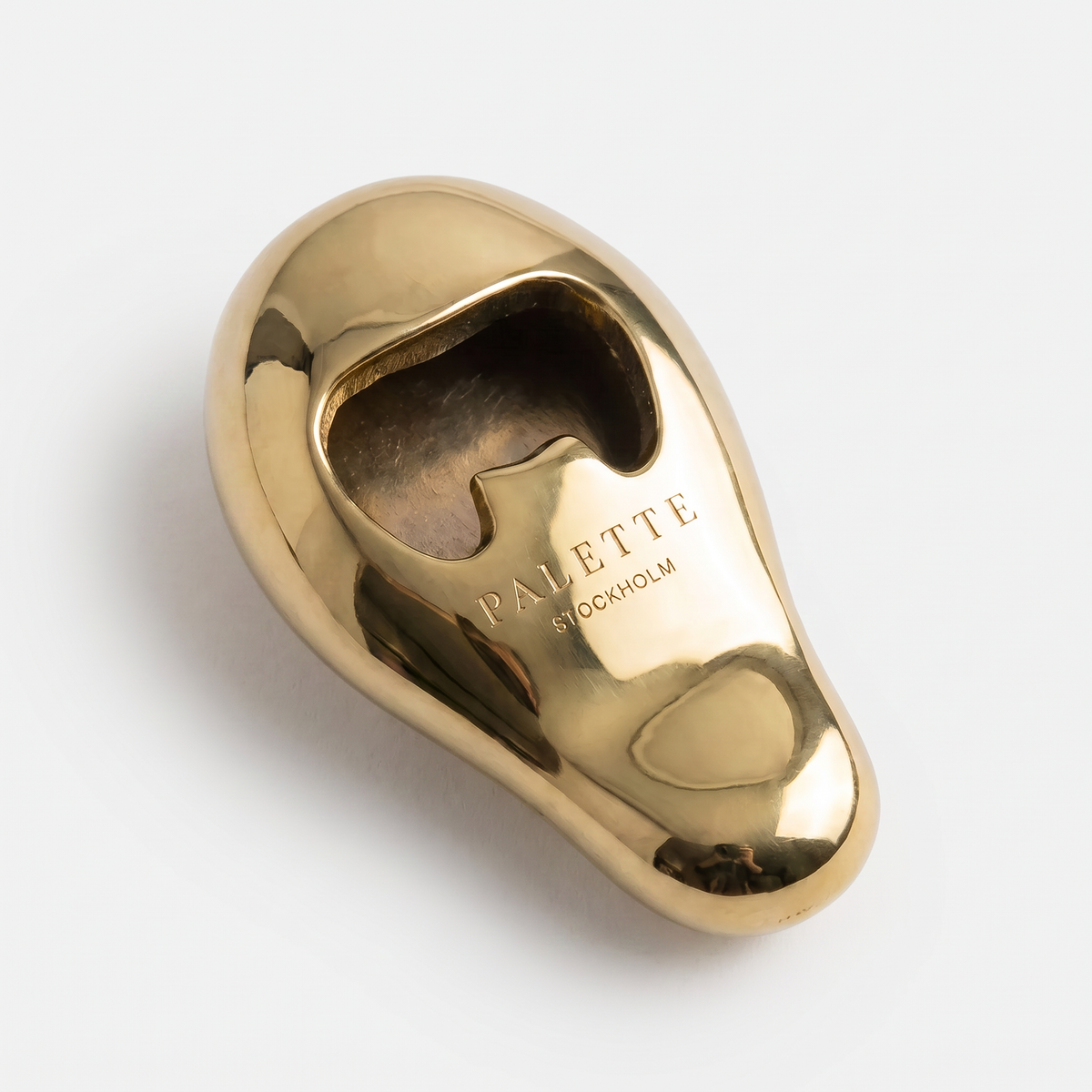 Vincent's Ear bottle opener in polished brass, styled on a table