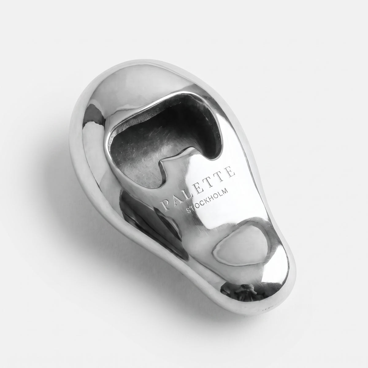 Vincent's Ear bottle opener in polished silver, styled on a table